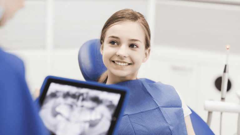 A smiling girl having her dental xrays explained