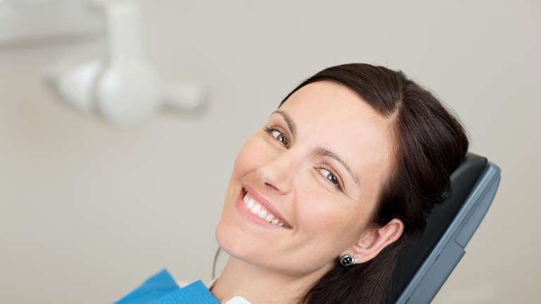 woman smiling in dentist exam chair | root canals centennial